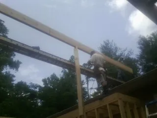 Carpenter setting a ridge beam over a new addition frame — Ice Dam Removal by Roofing Brothers in Old Fort