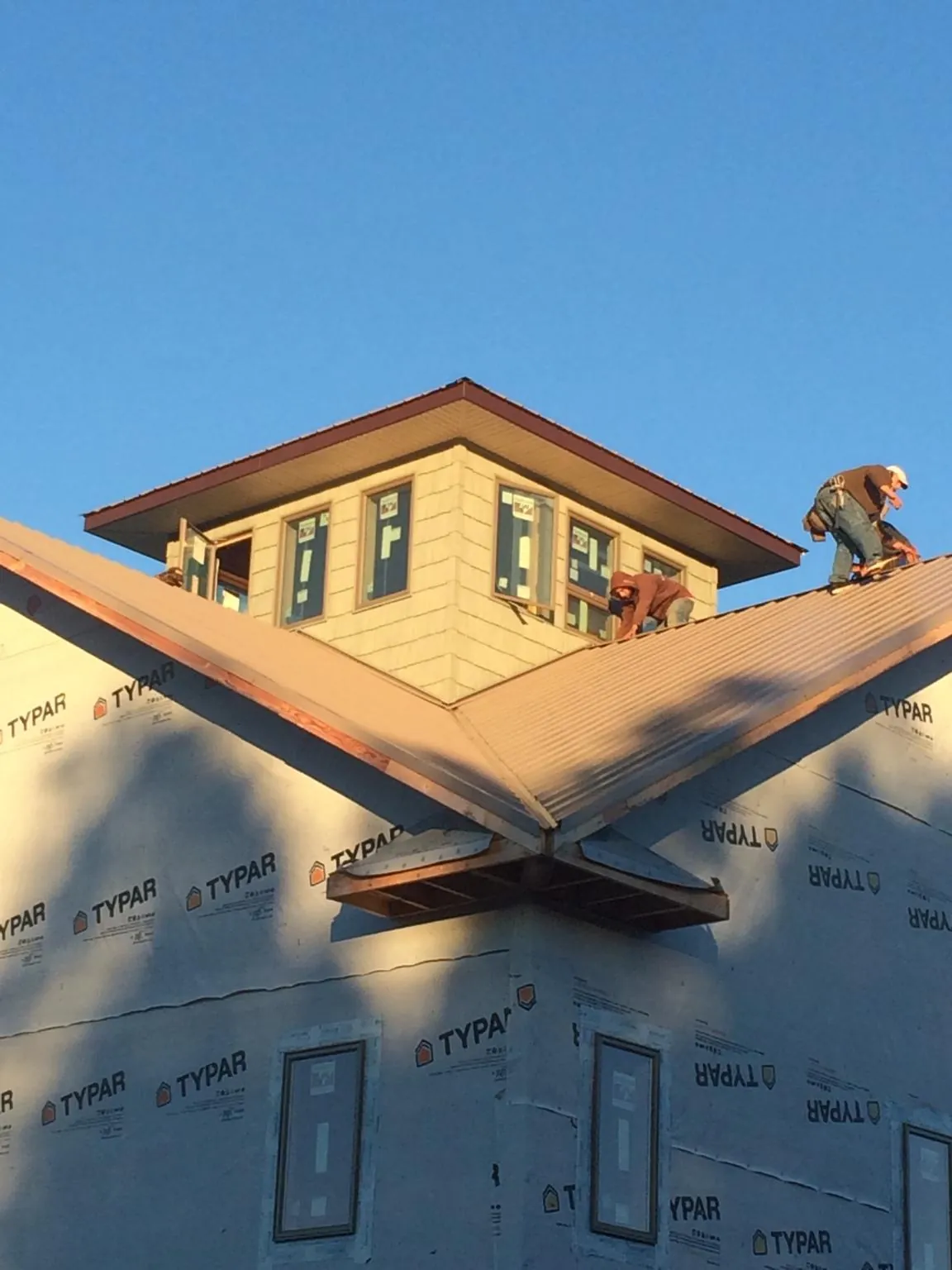 Roofers working around a rooftop cupola on a new metal roof at sunset — Roof Waterproofing in Old Fort by Roofing Brothers